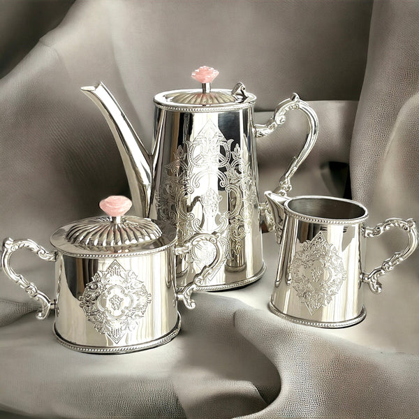 This luxurious rose quartz tea set in brass showcases an exquisite design with a shiny silver finish and rose quartz lids. Perfect for both elegant display and functional use, it adds a timeless touch of Victorian charm to any tea setting.